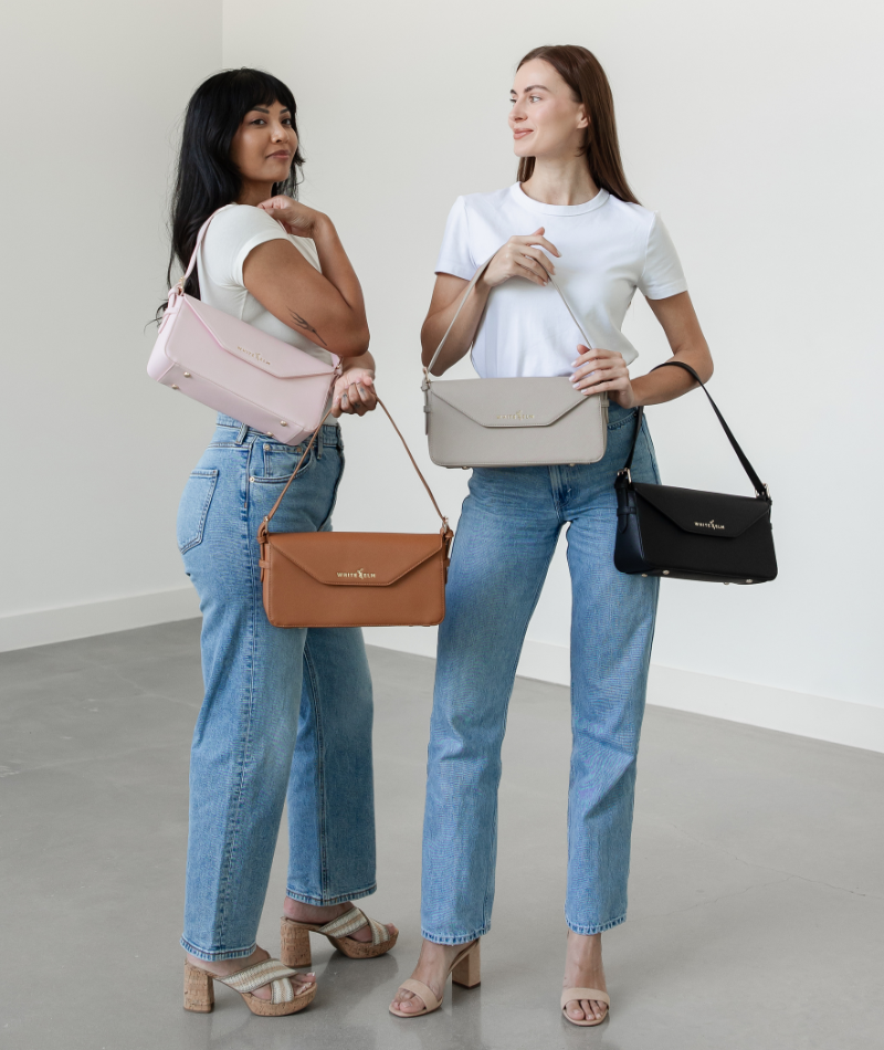 Blush pink Noemi shoulder bag held by the strap in front of the body