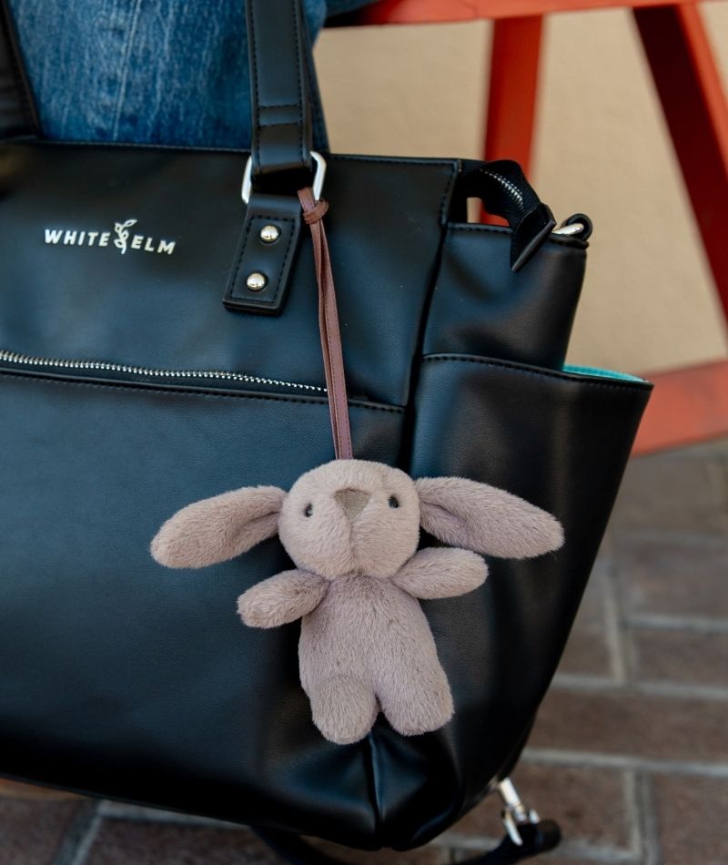 Taupe Emmy plush bunny bag charm attached to a black White Elm bag
