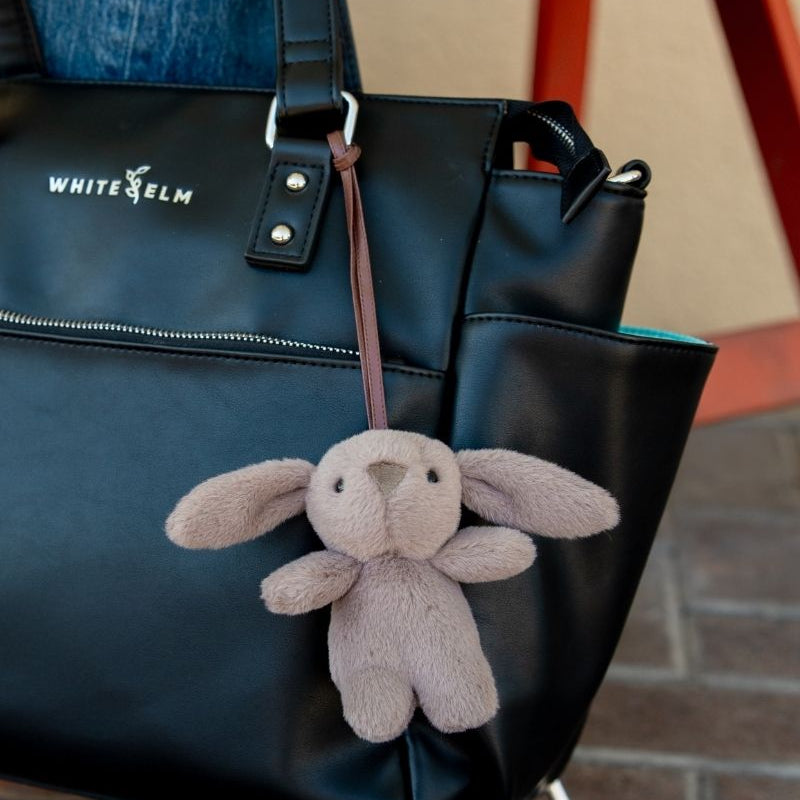 Taupe Emmy plush bunny bag charm attached to a black White Elm bag