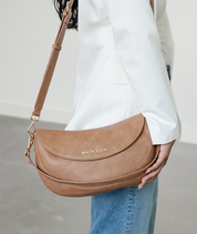 Woman wearing the Almond Emily Crescent bag over the shoulder