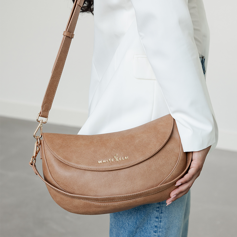 Woman wearing the Almond Emily Crescent bag over the shoulder