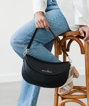 Woman holding the Black Emily Crescent bag by its strap