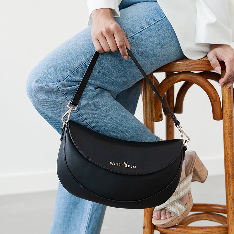 Woman holding the Black Emily Crescent bag by its strap