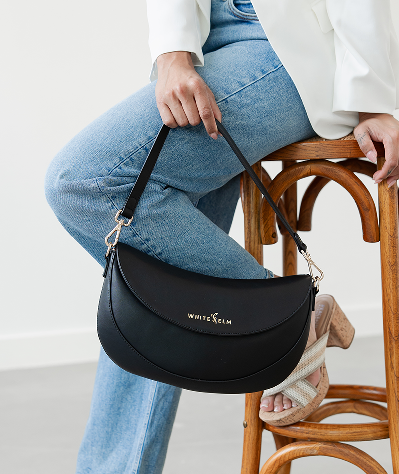 Woman holding the Black Emily Crescent bag by its strap