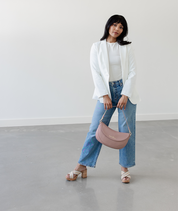 Woman holding the Dusty Rose Emily Crescent bag by its strap
