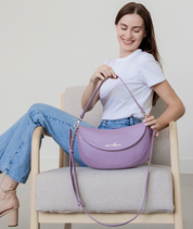 Woman holding the Heather Purple Emily Crescent bag by its strap