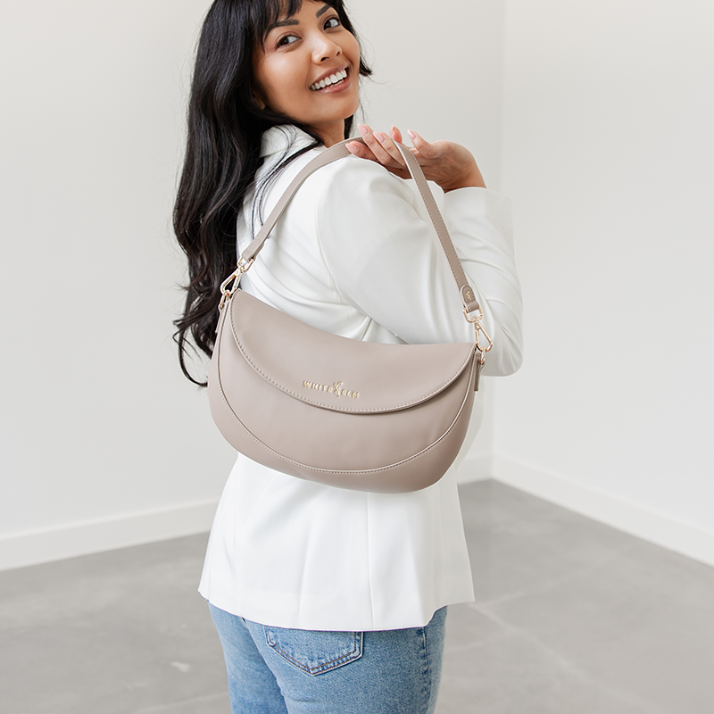 Woman holding the Taupe Emily Crescent bag by its strap