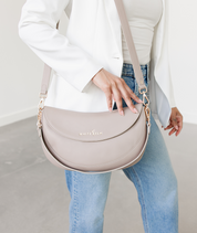 Woman wearing the Taupe Emily Crescent bag over the shoulder