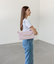 Blush pink Noemi shoulder bag worn over the shoulder, side profile